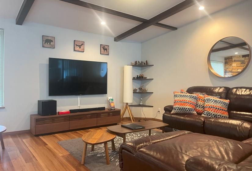 Modern living room with leather sofa and flat-screen TV at Zangetsu Niseko holiday rental
