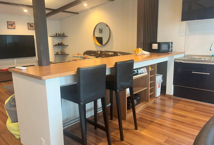 Open plan kitchen and dining area with breakfast bar and bar stools at Zangetsu Niseko holiday rental