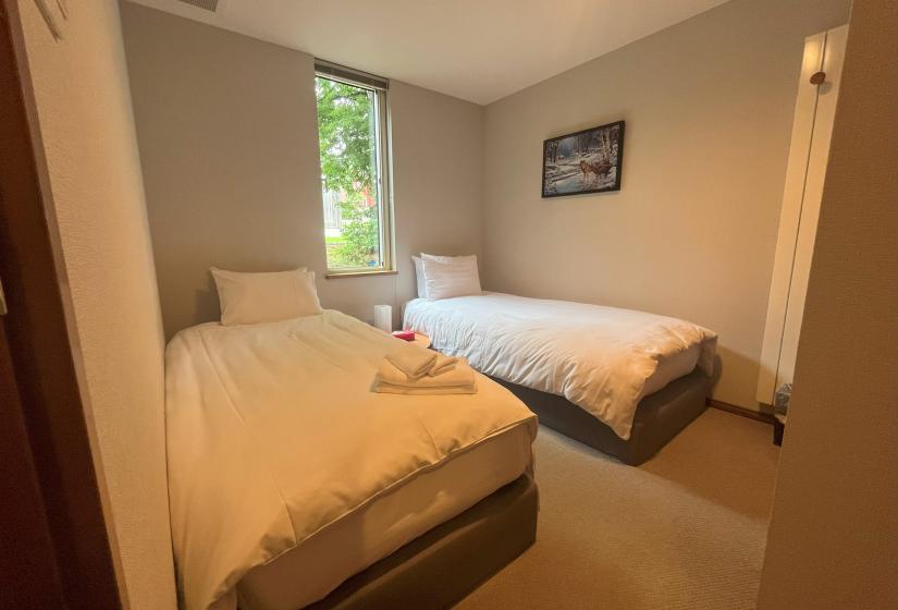 Twin bedroom with two single beds and mountain view window at Zangetsu Niseko holiday rental