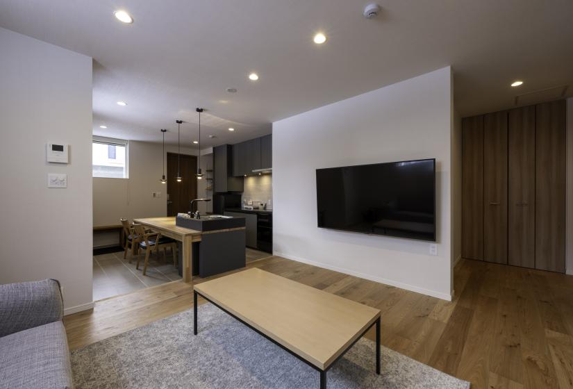 A TV on a wall and kitchen behind