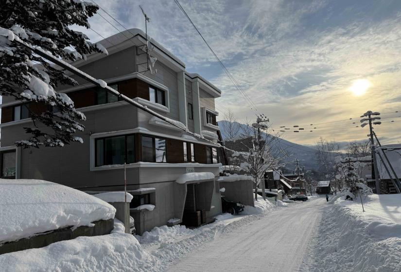 A snowy street with two story building to the left