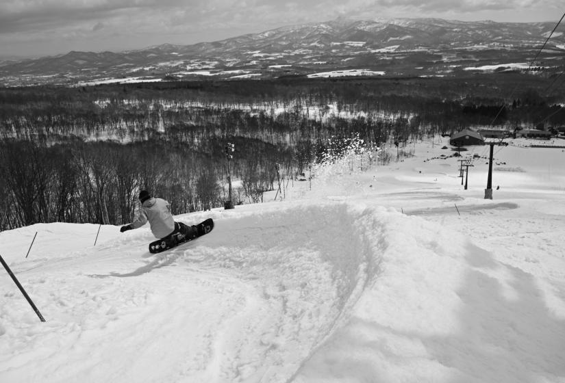 A snowboarder makes a turn on a bank