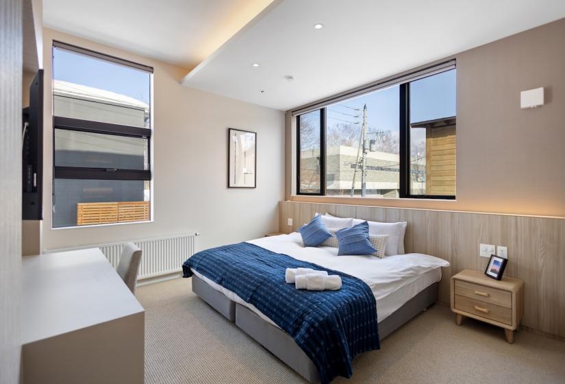 A made up double bed with blue throw