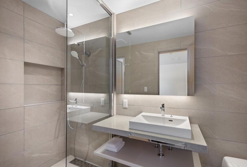 A bathroom basin and shower behind