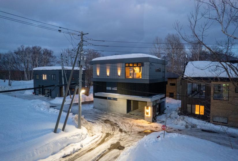 A two story house at dusk surrounded by snow