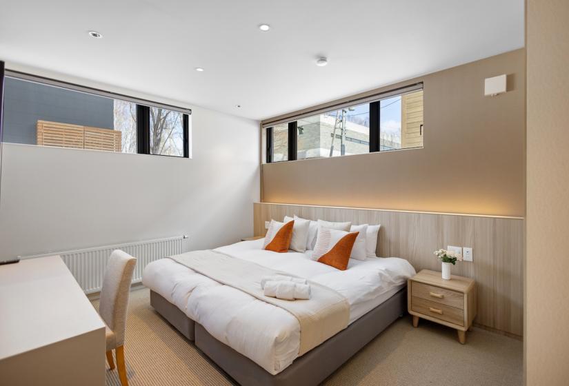 A made up double bed with beige throw