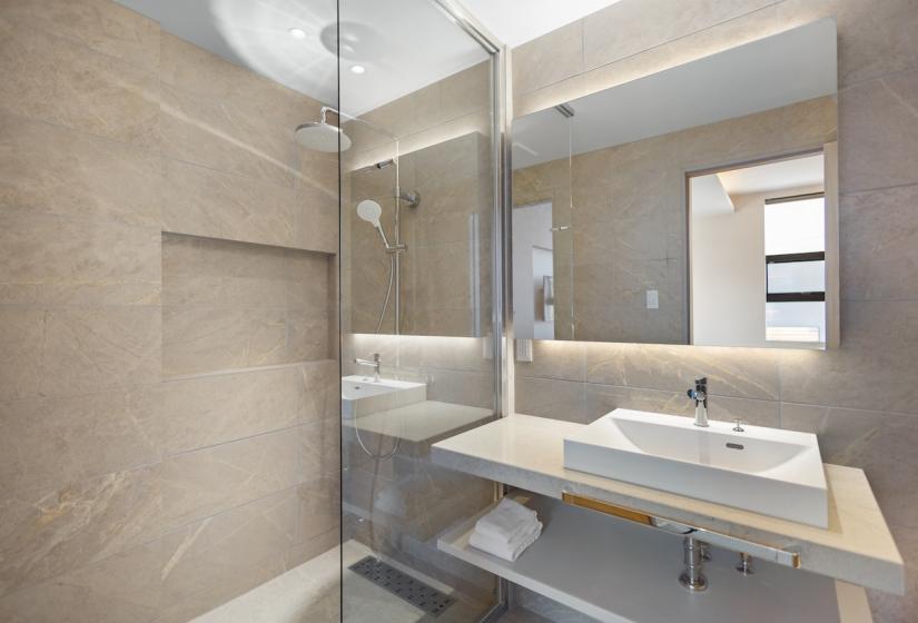A bathroom basin and shower behind