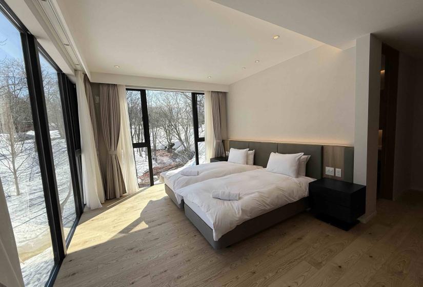A made white double bed with two windows to the left