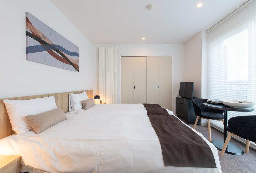 A made up double bed with brown throw