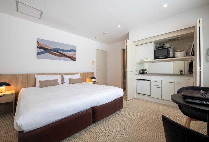 A made up double bed and kitchen to the right