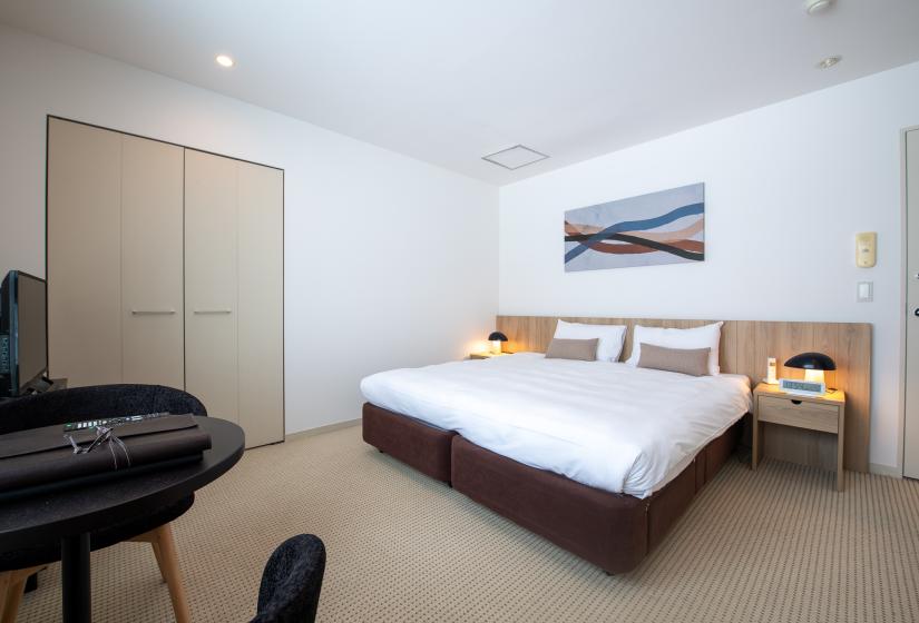 A made up double bed with picture above