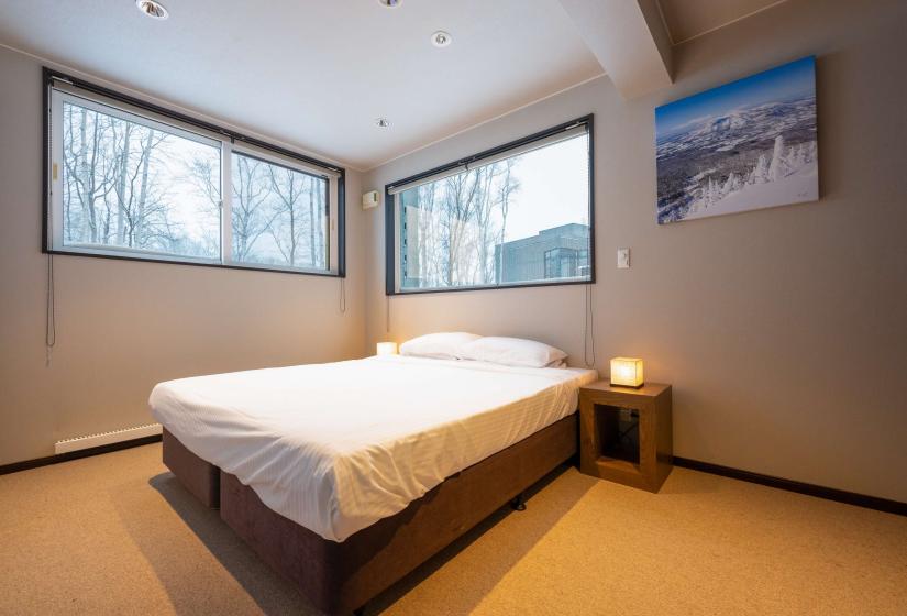 A made up double bed with windows behind