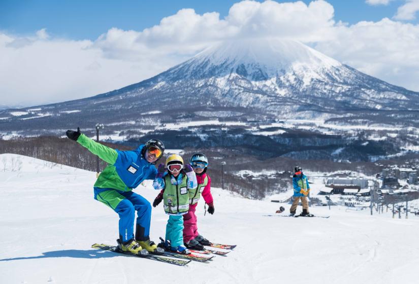 A ski instructor stands with two children