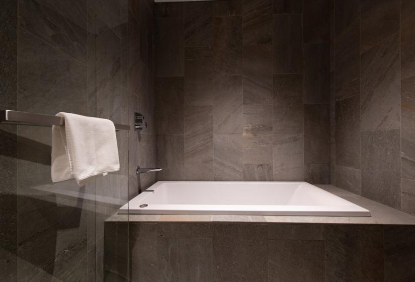 A white bath with dark tile surrounds