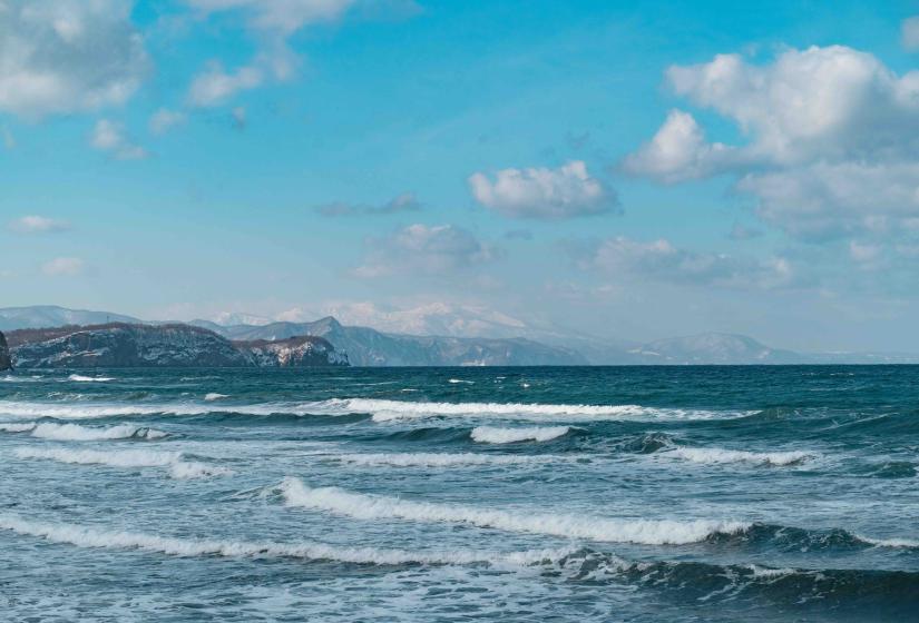 A choppy sea with mountains in the background