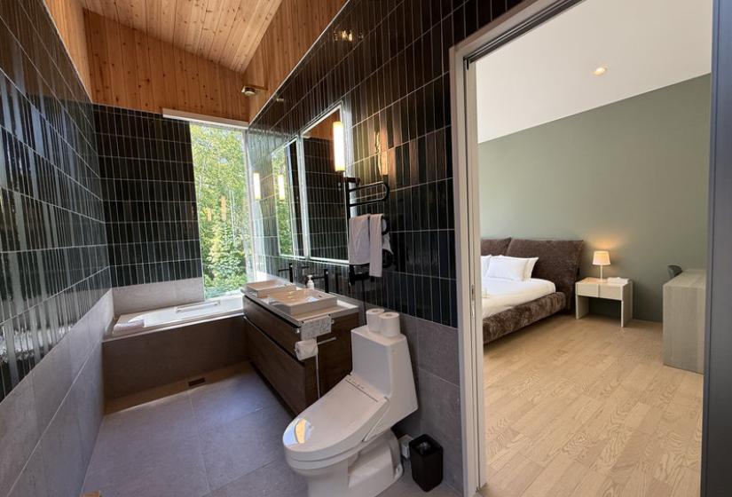 A green tiled bathroom with bath behind