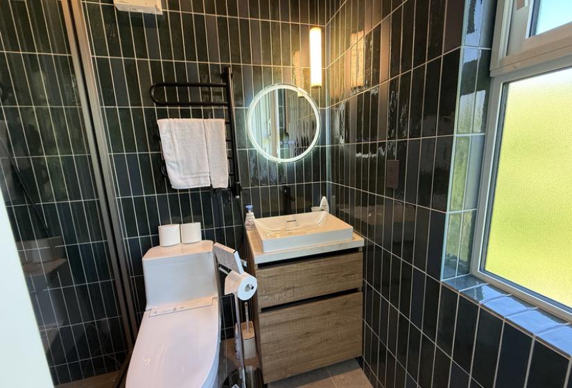 A green tiled bathroom with round mirror