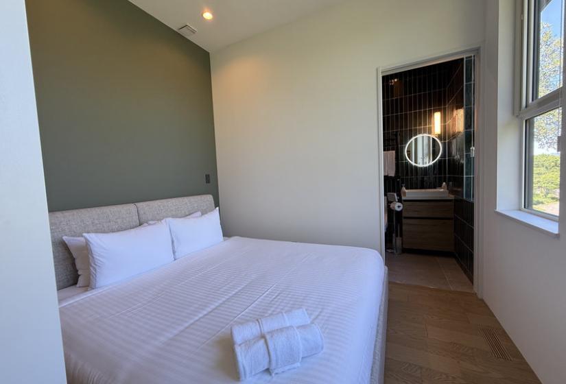 A made up double bed with towels at its foot.