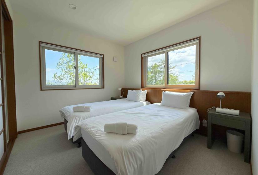 Two made up single beds with windows behind