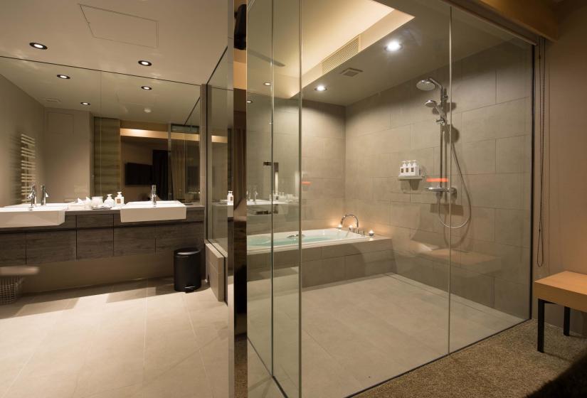 A light tiled bathroom with glass shower room