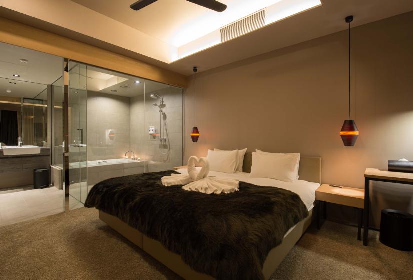 A made up double bed with bathroom behind