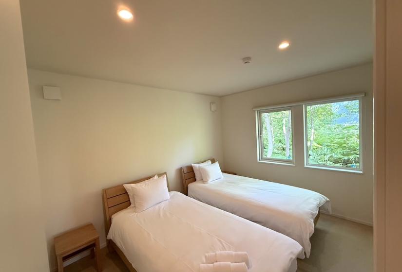Two made up single beds together with towels at their foot.