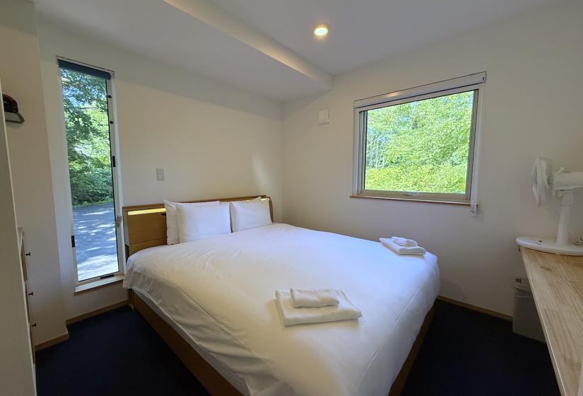 A made up double bed with window to the right