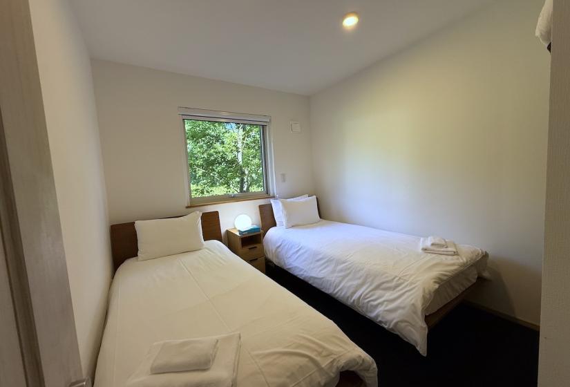Two made up single beds together with towels at their foot.